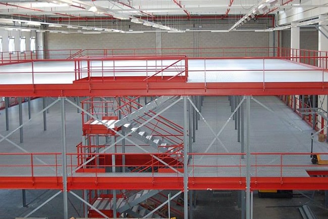 Struttura a soppalco multipiano con scale di sicurezza e parapetti installata in un capannone industriale a Milano